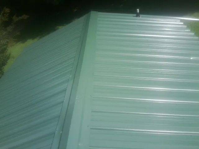 New green metal panels meeting at the ridge of a roof — Flat Roof Repair work by our crew in Warrendale