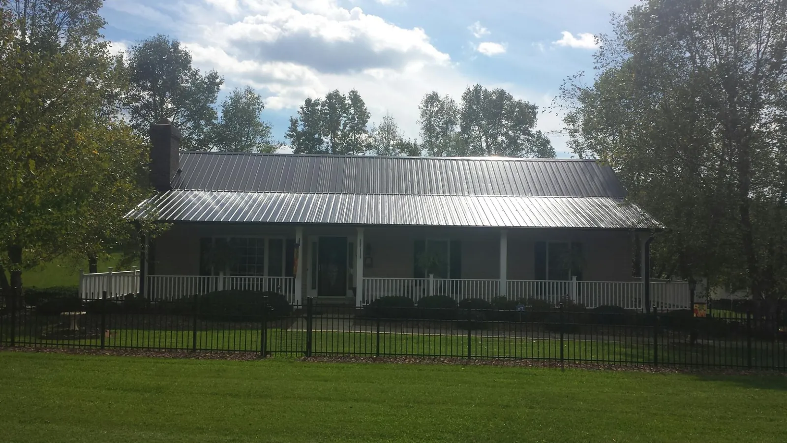 Gray metal roof on a brick ranch with a full width front porch — Gutter Guard Installation work by our crew in Warrendale