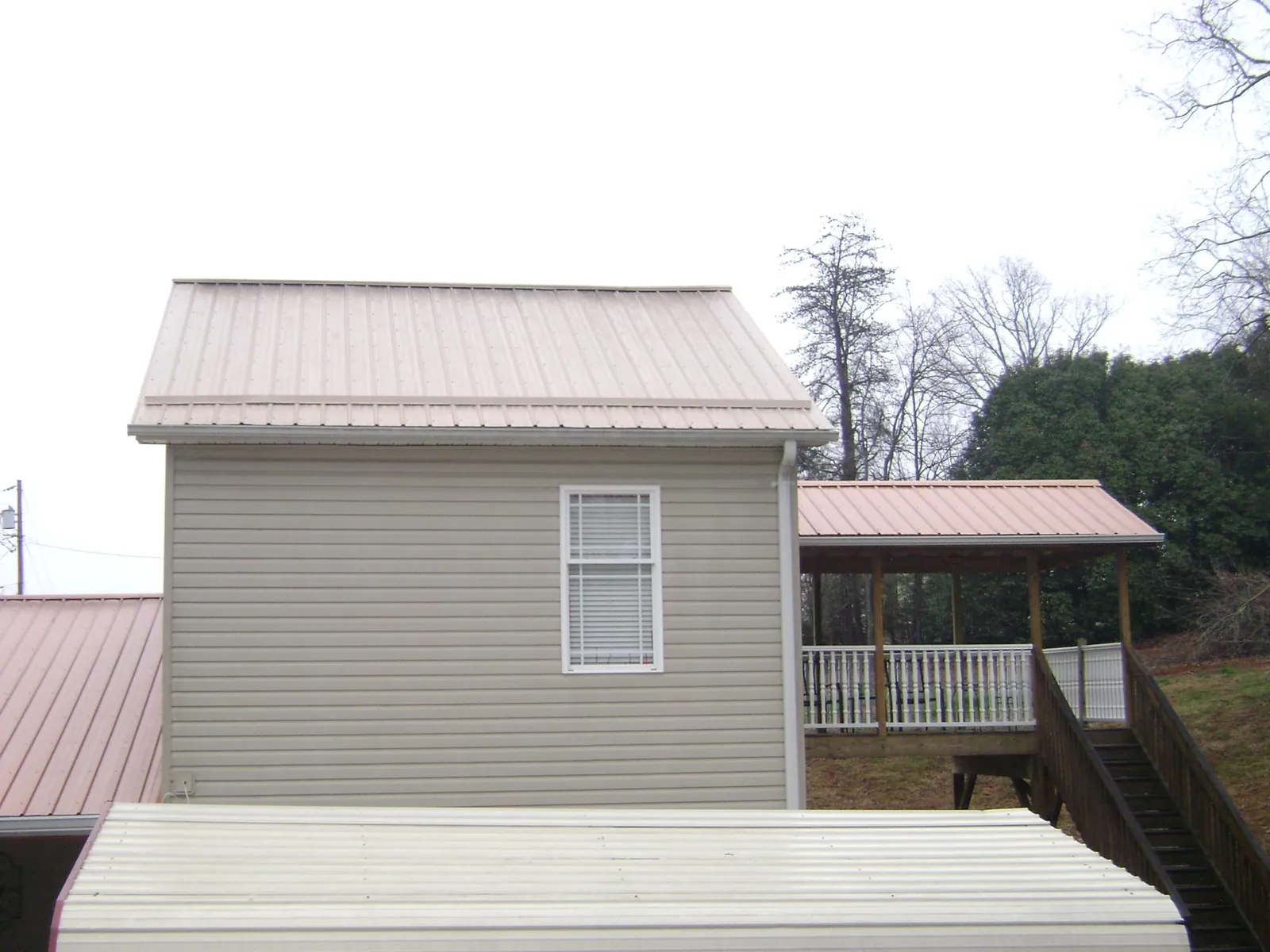 Tan metal roofs on a two story addition and attached porch, from a Roof Replacement job in Warrendale