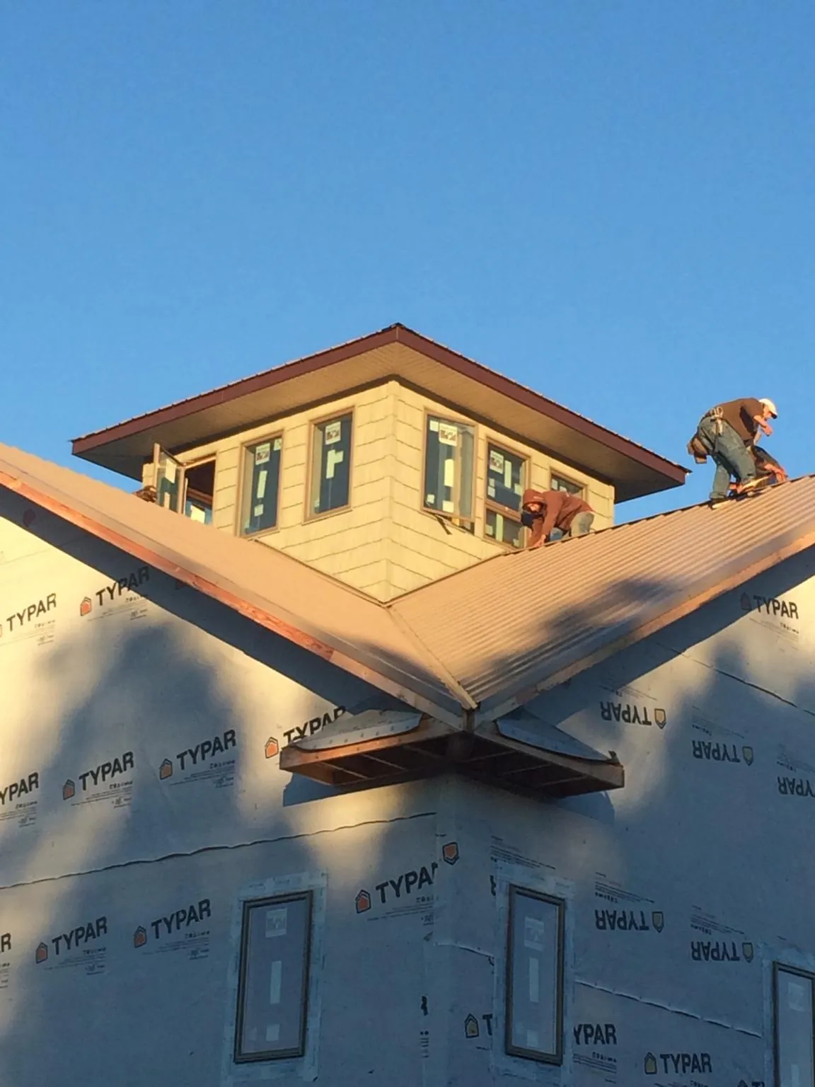 Roofers working around a rooftop cupola on a new metal roof at sunset — Roof Waterproofing in Warrendale by Roofing Brothers